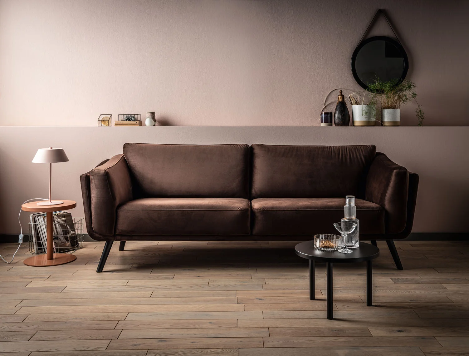 Czekoladowa sofa w salonie z beżową ścianą.